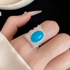 Gros plan d'une bague argentée texturée ornée d'une pierre ovale bleue vive