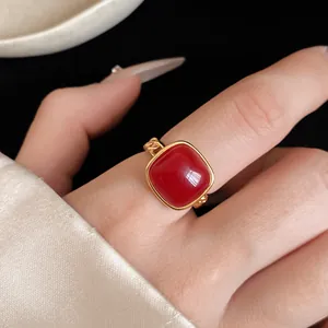 Vue macro d'une bague de luxe avec pierre carrée rouge sur un anneau doré à maillons.