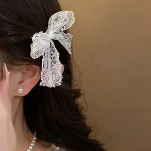 Close-up of a white lace bow hair clip worn in hair with elegant pearl accessories