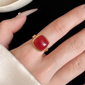 Gros plan d'une bague ouverte dorée ornée d'une pierre rouge éclatante taillée en coussin
