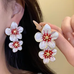 Detailed macro view of retro white enamel flower earrings with red floral centers
