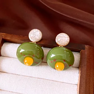 Primo piano di orecchini vintage in resina con accenti verde oliva e giallo di alta qualità