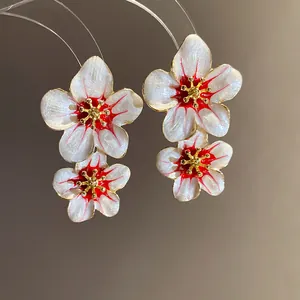 Macro view of vintage floral enamel earrings featuring white and red cherry blossom petals
