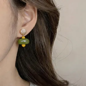 Elegante dettaglio ravvicinato di orecchini vintage in resina verde con perline gialle