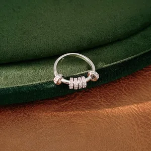 Close-up of a silver rotating ring with sparkling zircon stones on green velvet.