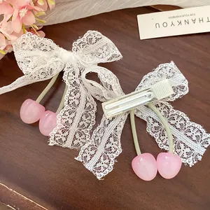 Close-up detail of white lace bow hair clips with sweet pink cherry charms on wood