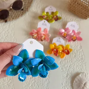 Gros plan de boucles d'oreilles orchidées tropicales en résine bleue, rose et orange
