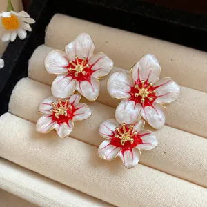 Close-up of elegant white and red enamel flower stud earrings in jewelry tray