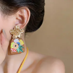 Dettaglio ravvicinato di orecchini a fiore artistici indossati da una modella con luce soffusa