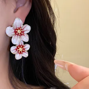 Close-up detail of elegant vintage enamel flower earrings shown on model's ear