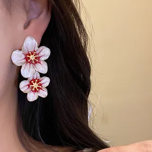 Close-up of elegant white enamel flower earrings worn on the ear