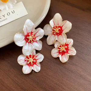 Close-up detail of vintage floral enamel earrings with red accents and gold center