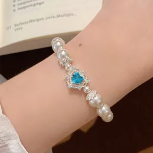 Macro view of dainty French vintage pearl bracelet featuring a heart blue gemstone