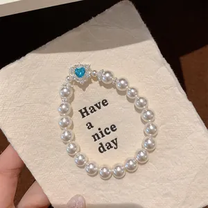 Detailed macro view of French vintage pearl beaded bracelet featuring a blue heart gemstone charm