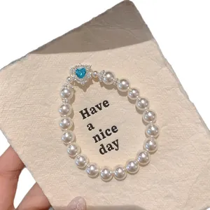 Elegant white pearl bead bracelet featuring a sparkling blue zircon heart centerpiece