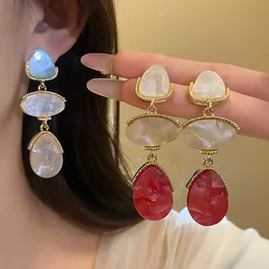Détail de boucles d'oreilles vintage en résine avec pendentifs gouttes marbrés rouges