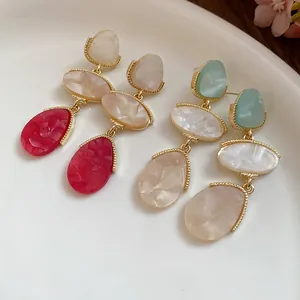 Détails macro des boucles d'oreilles vintage en résine avec des pendentifs dorés