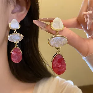 Vue détaillée de boucles d'oreilles vintage en résine avec pierres blanches et rouges.