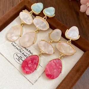 Vue détaillée de boucles d'oreilles en résine de style vintage dans un écrin.