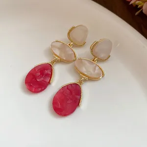 Détail de boucles d'oreilles vintage en résine avec élégante texture marbrée rouge et crème