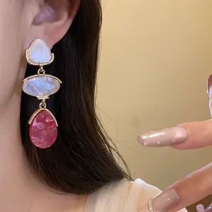 Détail de boucles d'oreilles vintage en résine avec pendentif goutte d'eau dorée