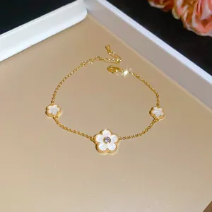 Elegant gold-plated bracelet featuring white enamel flower pendants with sparkling zircon centers