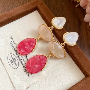 Détail de boucles d'oreilles pendantes vintage en résine avec pierres rouges marbrées