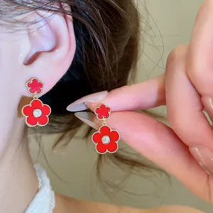 Close-up detail of red flower drop earrings featuring a zircon center and gold plating finish