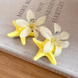 Detail of summer starfish hair clip with cream fabric flower and rhinestones
