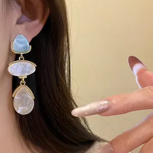 Détail des boucles d'oreilles vintage en résine de style palais doré sur modèle.