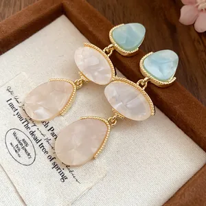Détail de boucles d'oreilles vintage en résine avec texture marbre et bord doré.