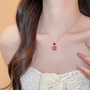 Close-up of a gold-plated necklace with red zircon flower pendants on a model.