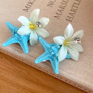 Close-up detail of summer blue starfish hair clips with white flower and sparkling crystal.