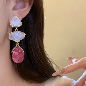 Vue détaillée de boucles d'oreilles pendantes en résine vintage sur l'oreille d'un modèle.