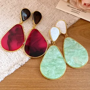 Close-up of vintage resin teardrop drop earrings in green and red with gold-toned frames