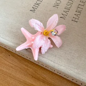 Close-up detail of a summer pink starfish and fabric flower hair clip with dewdrop accents