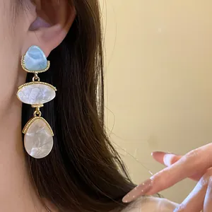 Détail de boucles d'oreilles vintage en résine avec monture dorée de style cour royale