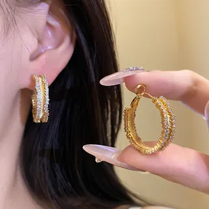 Detailed macro shot of gold-plated hoop earrings featuring sparkling double-row zircon