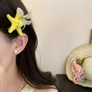 Close-up of a yellow starfish and flower hair clip worn on long dark hair, beach style.
