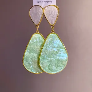 Close-up of light green marbled resin teardrop earrings with gold-tone frames