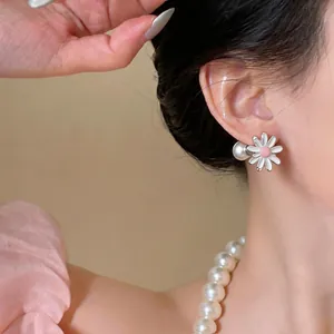 Close-up detail of a white daisy flower pearl stud earring being worn on an ear