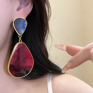 Macro view of vintage style red mottled resin teardrop earrings with gold metal frame
