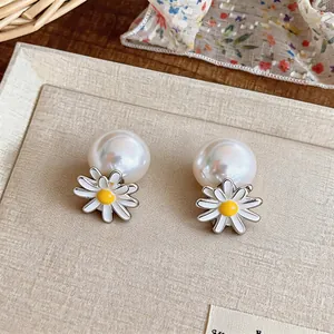 Detailed macro view of elegant daisy flower and large white pearl stud earrings set