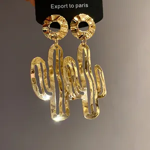 Nahaufnahme goldener Metallohrringe in Kaktusform mit einer einzigartigen Hammerschlag-Textur