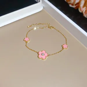 Close-up of gold plated bracelet with sweet pink enamel flowers and sparkling zircon center