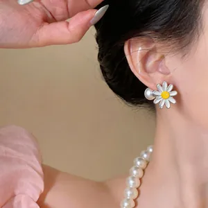 Close-up of elegant daisy flower earrings with pearl back worn by an Asian model