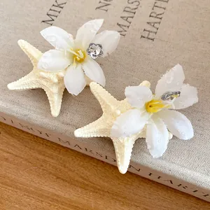 Detail showing texture of starfish and white flower hair clip with rhinestone