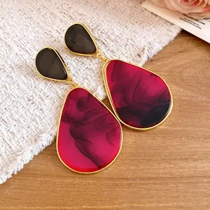 Macro detail of vintage resin teardrop dangle earrings featuring magenta marble patterns