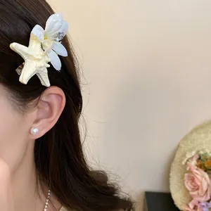 Close-up of starfish flower hair clip and pearl earring on model for summer vibes