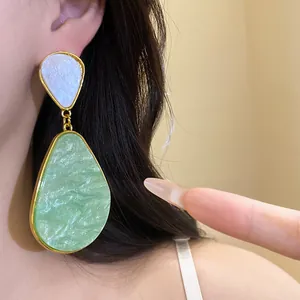 Close-up view of vintage resin drop earrings with green marble texture worn on ear